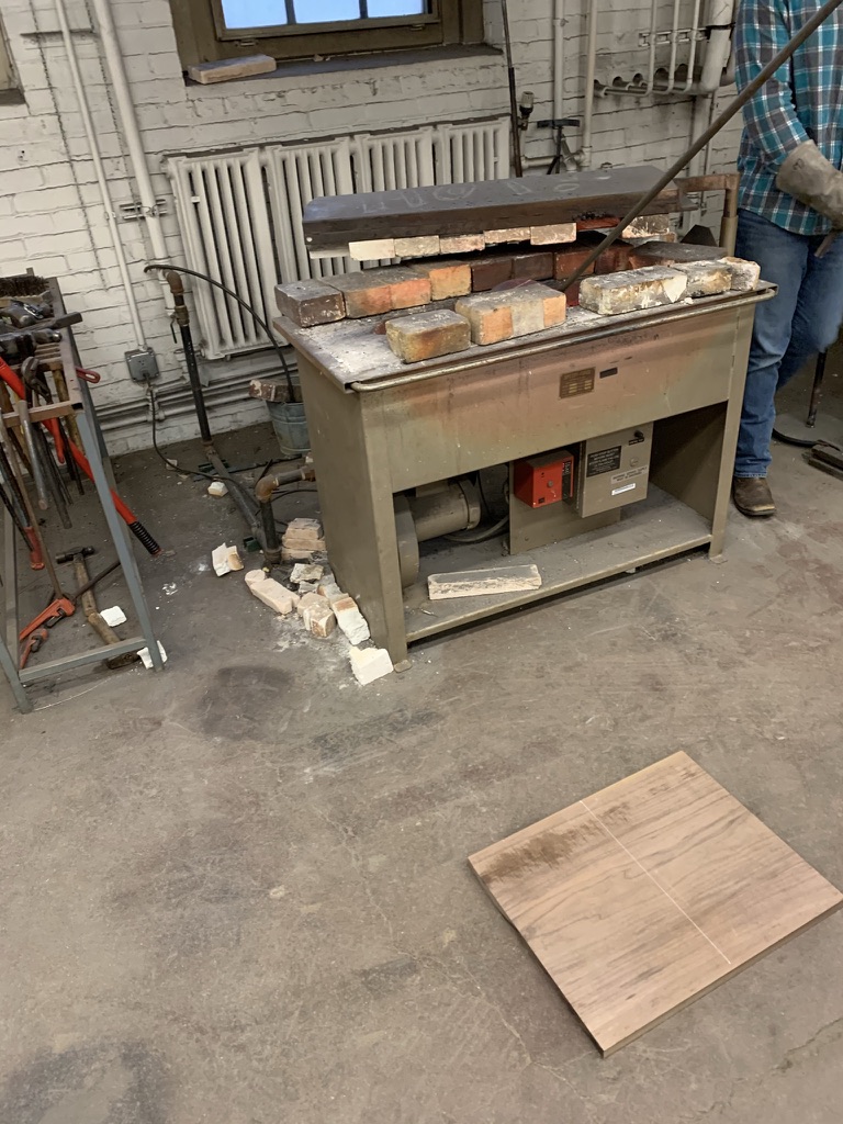 Heating the branding iron in a firebrick forge on a workshop bench