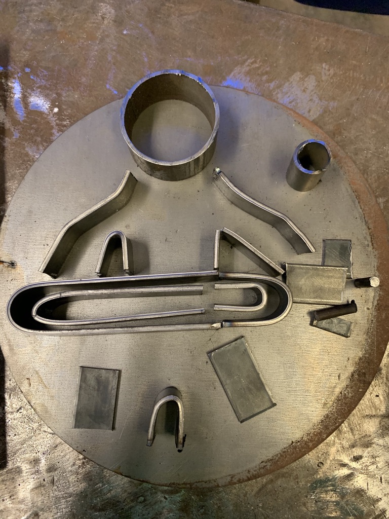 Steel branding-iron pieces laid out on a circular plate before welding